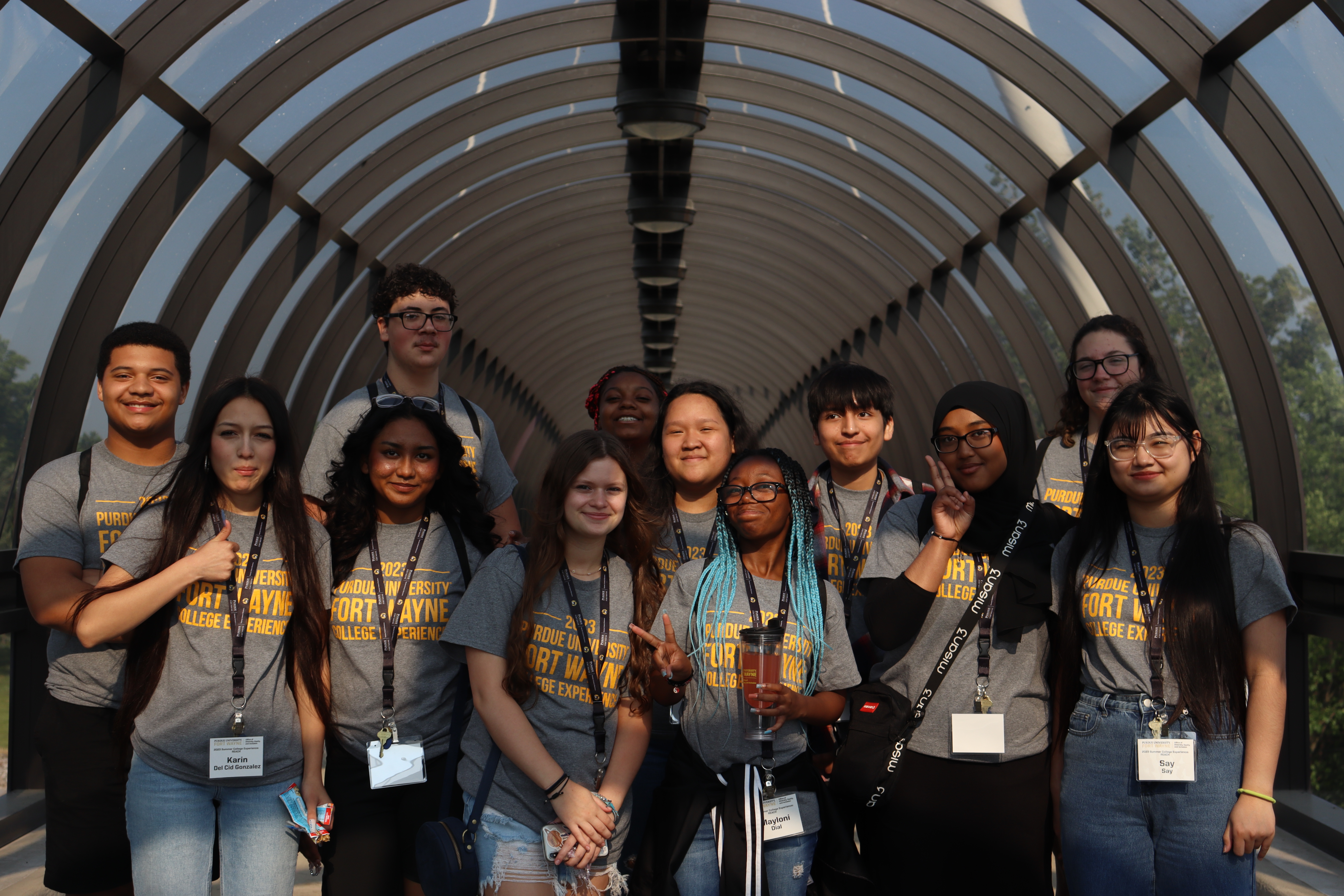 A group of students smile and pose for a photo on a bridge.